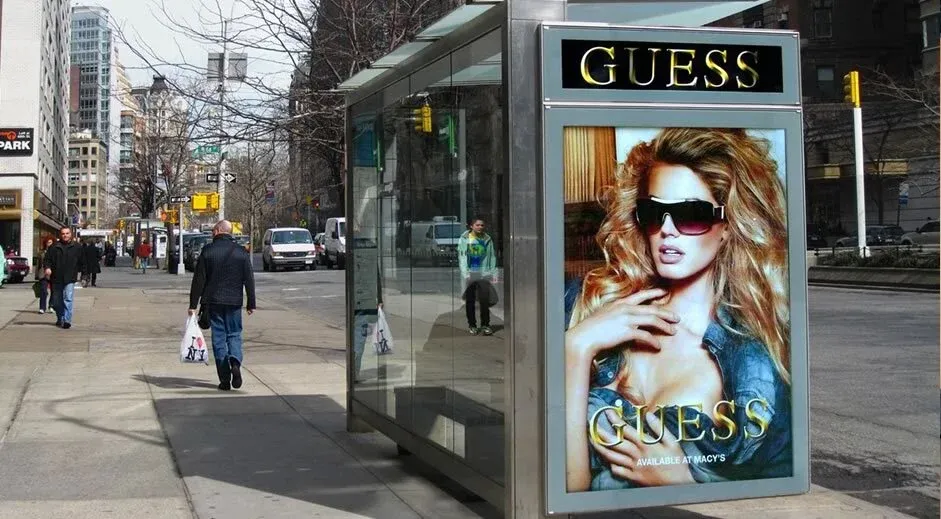 Guess campaign on a digital transit shelter screen on a New York street.
